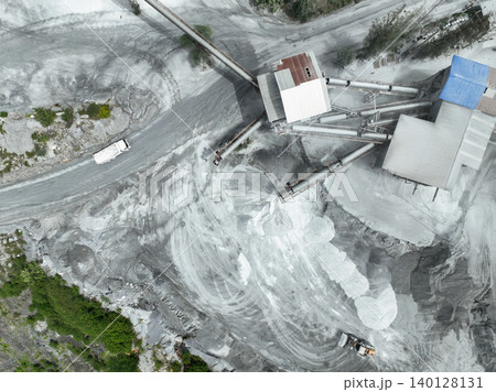 Aerial view of granite and limestone crushing plant with dump trucks and excavators processing raw stone into construction aggregates for concrete and infrastructure development. Stone mill factory. 140128131