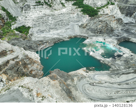 Open pit mine industry. Limestone quarry with truck. Heavy machinery in mining industry and construction material supply. Landscape of resource extraction in industrial site. Turquoise water lake. Open pit mine industry. Limestone quarry with truck. Heavy machinery in mining industry and construction material supply. Landscape of resource extraction in industrial site. Turquoise water lake. 140128136