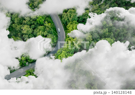 Aerial top view of electric vehicle driving on a winding highway road in green forest with fog. Sustainable transportation, zero emissions, and eco-friendly mobility for reducing carbon footprints. Aerial top view of electric vehicle driving on a winding highway road in green forest with fog. Sustainable transportation, zero emissions, and eco-friendly mobility for reducing carbon footprints. 140128148