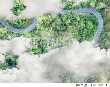 Aerial top view of electric vehicle driving on a winding highway road in green forest with fog. Sustainable transportation, zero emissions, and eco-friendly mobility for reducing carbon footprints. Aerial top view of electric vehicle driving on a winding highway road in green forest with fog. Sustainable transportation, zero emissions, and eco-friendly mobility for reducing carbon footprints. 140128151