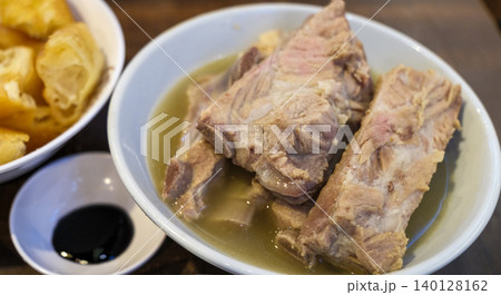 Bak kut teh or Bakut is a pork rib dish cooked in broth, served in Singapore. The Teochew style Bak kut teh which is light in colour but uses more pepper and garlic in the soup Bak kut teh or Bakut is a pork rib dish cooked in broth, served in Singapore. The Teochew style Bak kut teh which is light in colour but uses more pepper and garlic in the soup 140128162