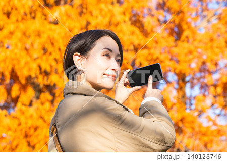紅葉をスマートフォンで撮影している女性　ライフスタイルイメージ 140128746