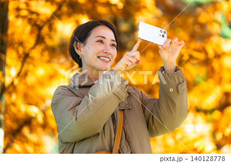 紅葉をスマートフォンで撮影している女性　ライフスタイルイメージ 140128778