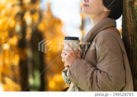 紅葉を楽しみながらホットドリンクを飲む女性 ライフスタイルイメージ 紅葉を楽しみながらホットドリンクを飲む女性 ライフスタイルイメージ 140128783