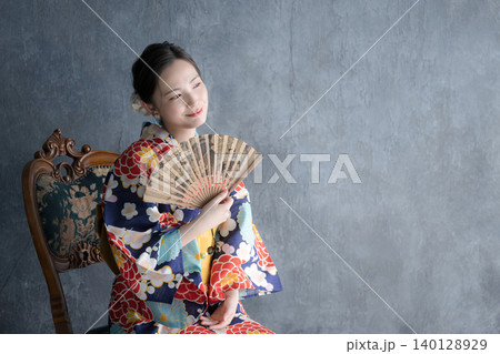 浴衣姿で扇子を持つ椅子に座る日本人女性の和風ビューティーポートレート	 140128929