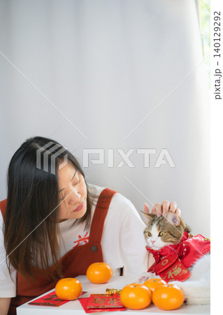 chinese new year concept with asian woman play with cat wearing red chinese traditional cloth with red envelope orange and gold on table chinese new year concept with asian woman play with cat wearing red chinese traditional cloth with red envelope orange and gold on table 140129292