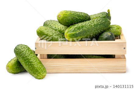 Pile of ripe cucumbers in a wooden box close-up on a white background. Isolated 140131115