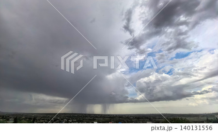 Massive storm cloud with visible rain over landscape Massive storm cloud with visible rain over landscape 140131556