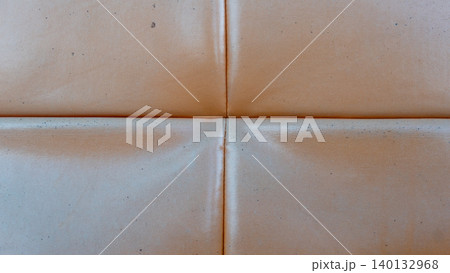 Showing the textured seams of an old brown leather sofa surface. Crossed stitching creates a quadrant pattern across the worn vintage material fabric. Showing the textured seams of an old brown leather sofa surface. Crossed stitching creates a quadrant pattern across the worn vintage material fabric. 140132968