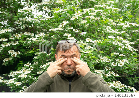 Senior man allergic suffering from seasonal allergy near blooming tree Senior man allergic suffering from seasonal allergy near blooming tree 140133367