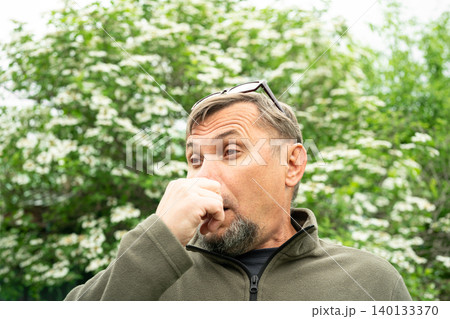 Senior man allergic suffering from seasonal allergy near blooming tree Senior man allergic suffering from seasonal allergy near blooming tree 140133370
