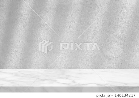 White Marble Table Set Against White Stucco Wall with Light Beam and Shadow White Marble Table Set Against White Stucco Wall with Light Beam and Shadow 140134217