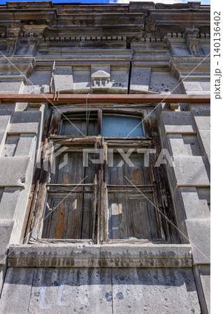 Decaying wooden window set into weathered stone facade Decaying wooden window set into weathered stone facade 140136402