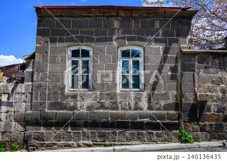 Weathered gray stone building with arched windows Weathered gray stone building with arched windows 140136435