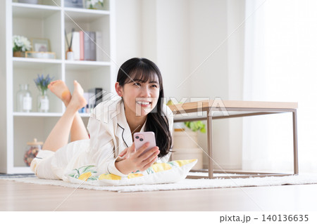 パジャマ姿でスマホを見る若い女性 パジャマ姿でスマホを見る若い女性 140136635