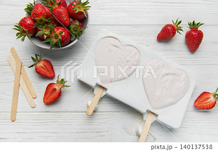 Preparing strawberry yogurt popsicles in heart shaped molds Preparing strawberry yogurt popsicles in heart shaped molds 140137538