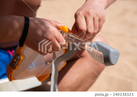 Caucasian man prepares snorkeling mask on a beach in Sharm El Sheikh Egypt with close view of diving equipment and sandy background. Snorkeling and marine recreation Caucasian man prepares snorkeling mask on a beach in Sharm El Sheikh Egypt with close view of diving equipment and sandy background. Snorkeling and marine recreation 140138323