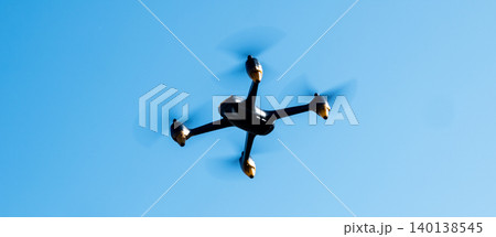 Black drone fllying in the blue sky. Innovative modern technology for work, game or entertainment. Black drone fllying in the blue sky. Innovative modern technology for work, game or entertainment. 140138545