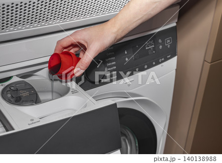 Woman pouring liquid detergent into washing machine drawer. Adult female adding cleaning product in laundry room. Domestic cleaning concept for home, household, lifestyle.. 140138988