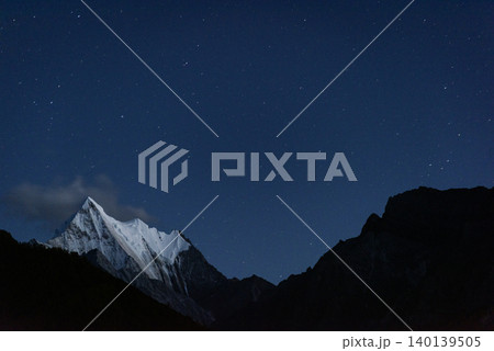night view of snow mountain, the view of mountains.long exposure shot of the galaxy and the starry sky over mountain and lake in yading national park, daocheng county, sichuan province, china 140139505