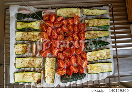 Baked cherry tomatoes Zucchini and onion on a baking rack Baked cherry tomatoes Zucchini and onion on a baking rack 140139860