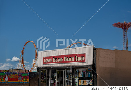 New york, usa august 21,2024. Iconic coney island beach shop on a sunny day with the parachute jump and a roller coaster loop visible in the background. Coney island theme park New york, usa august 21,2024. Iconic coney island beach shop on a sunny day with the parachute jump and a roller coaster loop visible in the background. Coney island theme park 140140118