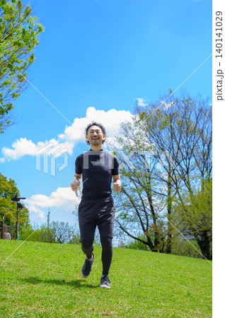 ペットボトルを持ってランニングをするスポーツウェアの日本人男性 140141029