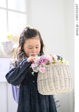 ランドセルを背負って花の入ったカゴを眺める日本人の女の子 ランドセルを背負って花の入ったカゴを眺める日本人の女の子 140141047