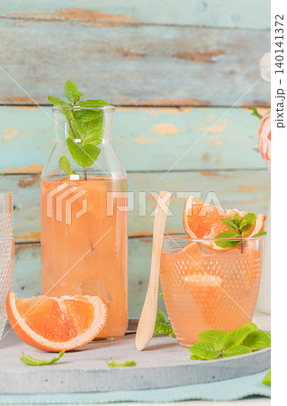 Grapefruit juice with mint in glasses on the table. Refreshing summer cocktail. 140141372