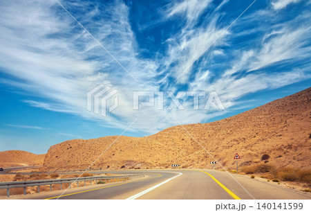 Driving a car on the mountain road in the desert. View of sandstone mountains through the windscreen. The road from Arad to the Dead Sea. Israel 140141599