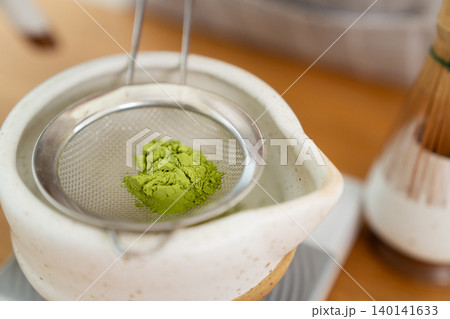 Woman whisking Matcha green tea with bamboo Chasen in bowl Woman whisking Matcha green tea with bamboo Chasen in bowl 140141633