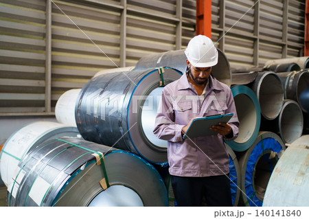 Young hispanic engineer inspecting metal roll in factory 140141840