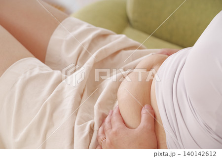 お腹のぜい肉を気にする女性 お腹のぜい肉を気にする女性 140142612