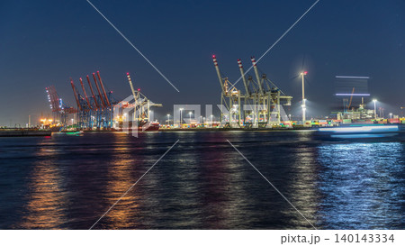 Night timelapse of Hamburg cargo port, showcasing container terminals, cranes and cargo ships on the Elbe River. Night timelapse of Hamburg cargo port, showcasing container terminals, cranes and cargo ships on the Elbe River. 140143334