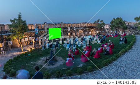 People are enjoying the open air cinema in the hictoric building at evening timelapse 140143385