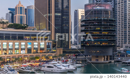 Aerial view of Dubai Marina with shopping mall, restaurants, towers and yachts day to night timelapse, United Arab Emirates. 140143440