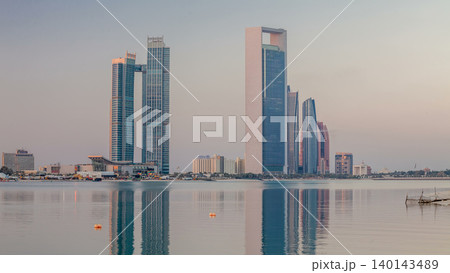 Abu Dhabi city skyline with skyscrapers before sunrise with water reflection night to day timelapse Abu Dhabi city skyline with skyscrapers before sunrise with water reflection night to day timelapse 140143489