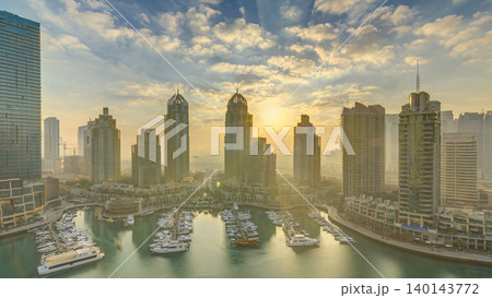 View of modern skyscrapers shining in sunrise lights timelapse in Dubai Marina in Dubai, UAE. View of modern skyscrapers shining in sunrise lights timelapse in Dubai Marina in Dubai, UAE. 140143772