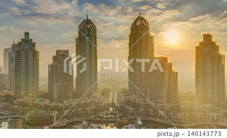 View of modern skyscrapers shining in sunrise lights timelapse in Dubai Marina in Dubai, UAE. View of modern skyscrapers shining in sunrise lights timelapse in Dubai Marina in Dubai, UAE. 140143773
