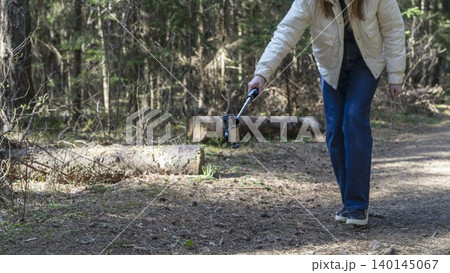 Woman walking in forest with smartphone on gimbal stabilizer. Outdoor content creation on a woodland trail. Mobile video recording gear for travel and social media.. Woman walking in forest with smartphone on gimbal stabilizer. Outdoor content creation on a woodland trail. Mobile video recording gear for travel and social media.. 140145067