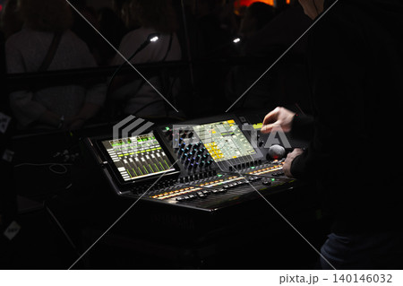 Live sound engineer adjusts a digital mixing console 140146032