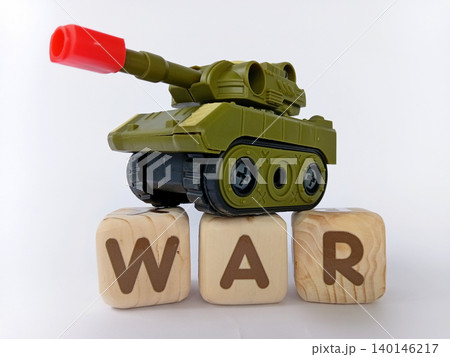 A toy military tank on a wooden block with the word WAR written on it. War news concept. A toy military tank on a wooden block with the word WAR written on it. War news concept. 140146217