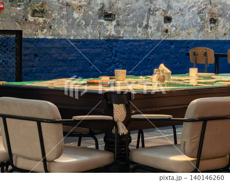 A vintage pool table is repurposed as a dining area in a rustic industrial loft with cream chairs for a unique creative cafe atmosphere that blends leisure with urban interior style A vintage pool table is repurposed as a dining area in a rustic industrial loft with cream chairs for a unique creative cafe atmosphere that blends leisure with urban interior style 140146260
