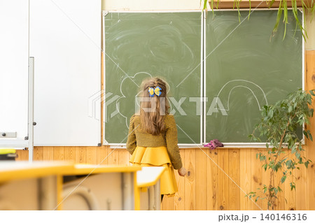 Young girl drawing a cloud and rainbow on a school chalkboard in a bright classroom, representing childhood creativity, early education, and learning in a supportive academic setting Young girl drawing a cloud and rainbow on a school chalkboard in a bright classroom, representing childhood creativity, early education, and learning in a supportive academic setting 140146316