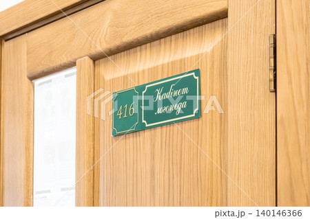 Green speech therapist office sign with number 416 mounted on a light wood door in a medical or educational institution, conveying professional guidance and health support service 140146366