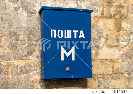 Blue metal mailbox mounted on a textured stone wall in an outdoor urban setting, symbolizing local postal communication and historical city architecture within a classic street scene Blue metal mailbox mounted on a textured stone wall in an outdoor urban setting, symbolizing local postal communication and historical city architecture within a classic street scene 140146372