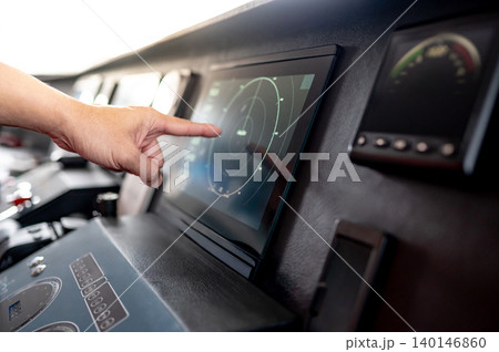 Captain hand pointing at marine radar monitor or GPS navigation on boat dashboard 140146860