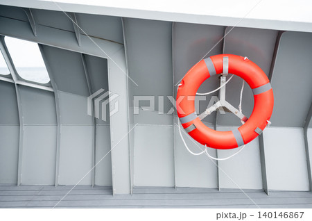 Orange lifebuoy or life preserver ring hanging on side wall of steel boat Orange lifebuoy or life preserver ring hanging on side wall of steel boat 140146867