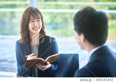 手帳を手に笑顔で商談する日本人ビジネスウーマン 手帳を手に笑顔で商談する日本人ビジネスウーマン 140147242