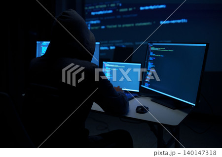 Hacker in Hoodie Working on Multiple Code Monitors 140147318